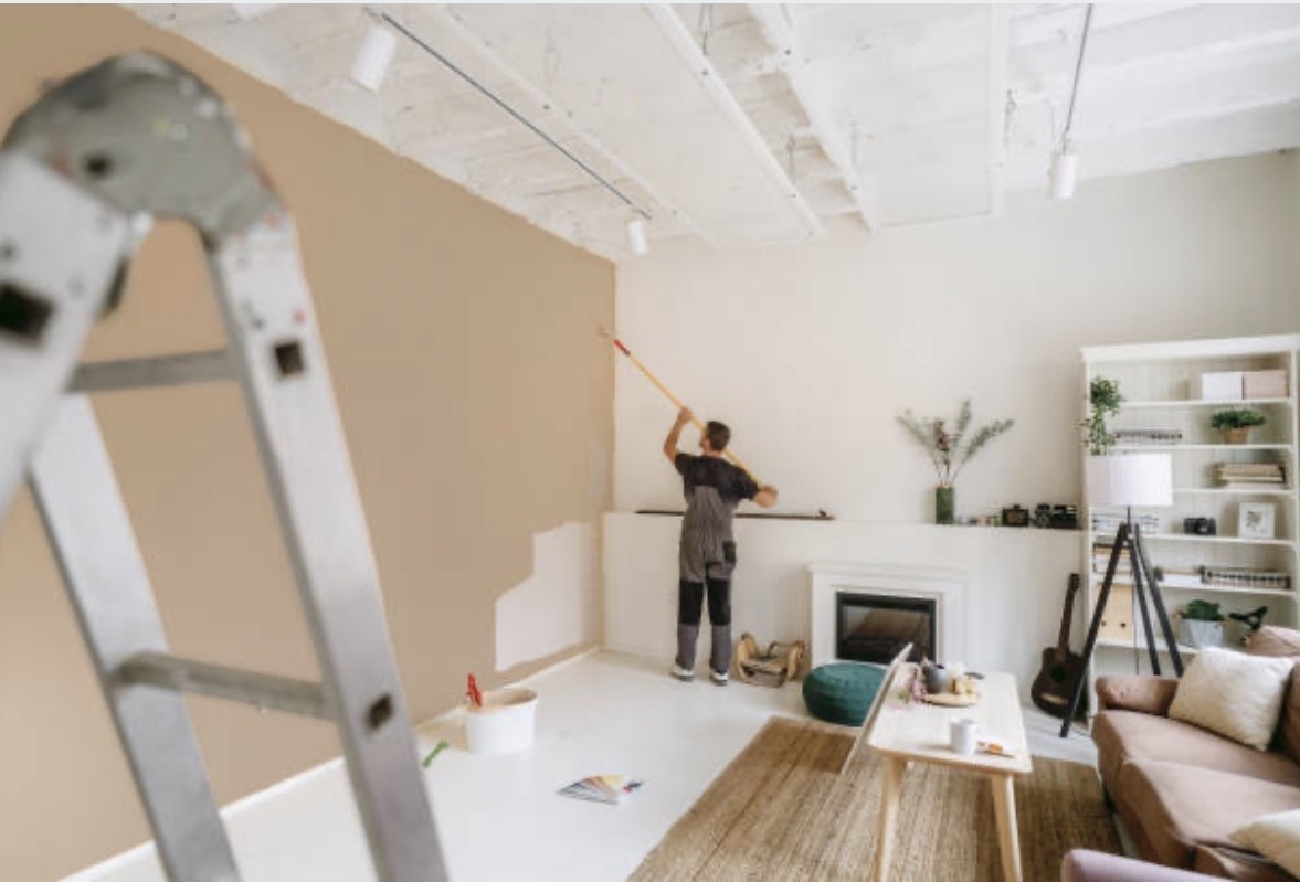 Professional interior painter rolling a warm neutral wall in a Portland living room